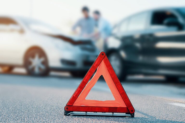 Triangolo di emergenza sull’asfalto davanti a due auto incidentate