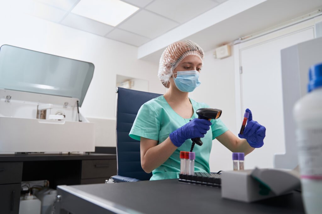 Una tecnica di laboratorio registra le provette di un prelievo in ospedale